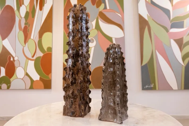 Esculturas de cactos com pinturas contemporâneas ao fundo